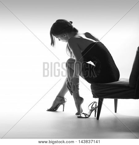 Beautiful sitting woman instudio with high heel shoes, white background