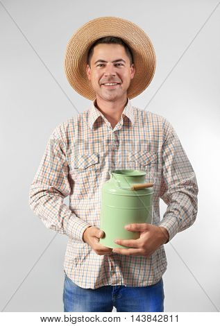 Milkman with watering can on light background