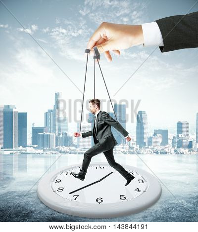 Huge hand making employee run on abstract clock. City background. Manipulation and control concept