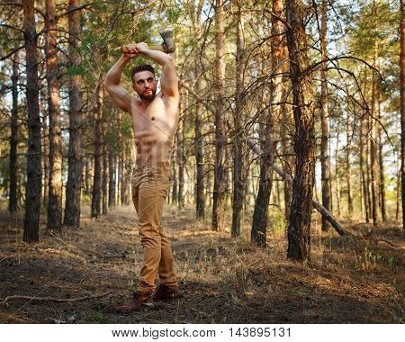 Lumberjack swings ax. Woodcutter with a naked torso. Felling trees. Logging. Manual labor.