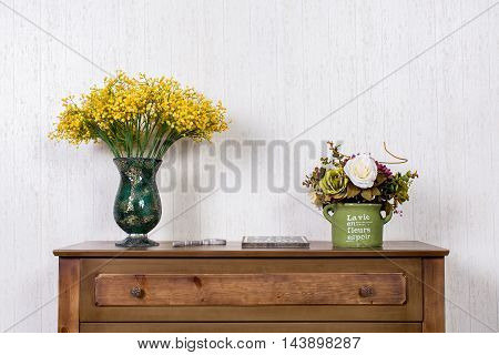 Close-up vase with flovers on dresser in home inrerrior