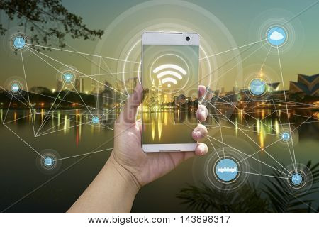 Hand holding white phone with city scape and wifi network connection concept