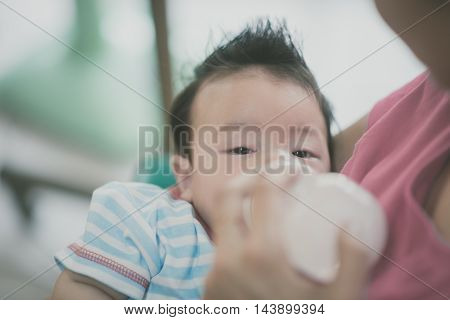 Baby drinkink mother breast feeding milk from bottle mother holding