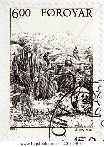 LUGA RUSSIA - JUNE 25 2016: A stamp printed by FAROE ISLANDS shows Faroese peasants fleecing sheep in farm circa 1995.