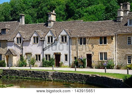 Stone cottages alongside the river Bybrook Castle Combe Wiltshire England UK Western Europe.