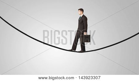 A confident smiling salesman balancing on black wire in clear grey empty space concept