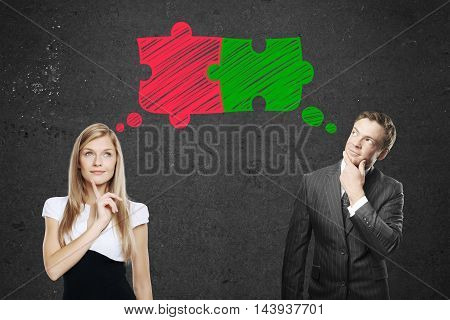 Young businessman and businesswoman thinking about putting colorful puzzle pieces together on concrete background. Teamwork and partnership concept