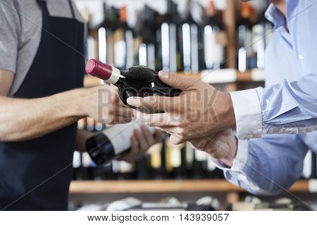 Midsection Of Customer And Salesman With Wine Bottles
