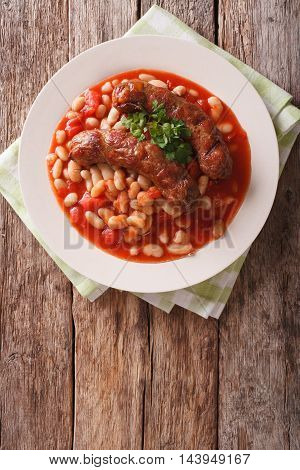 Grilled Sausage With Beans In Tomato Sauce On A Plate Close-up. Vertical Top View