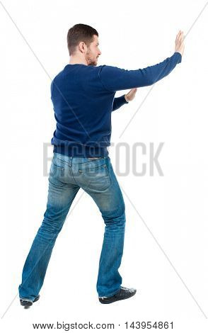 back view of business man pushes wall. Isolated over white background. Rear view people collection. backside view of person. bearded man in blue pullover shoves something on the side.