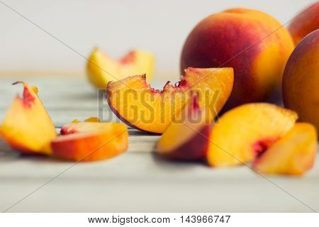 Whole peaches and slices on white wooden board