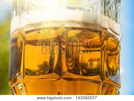 beer in glass on a green natural background rife with sunlight sky closeup