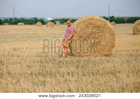 Man Resting After Hay Harvesting In Haystacks