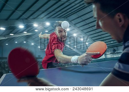 The Table Tennis Player In Motion. Fit Young Sports Man Tennis-player In Play On Sport Arena Backgro