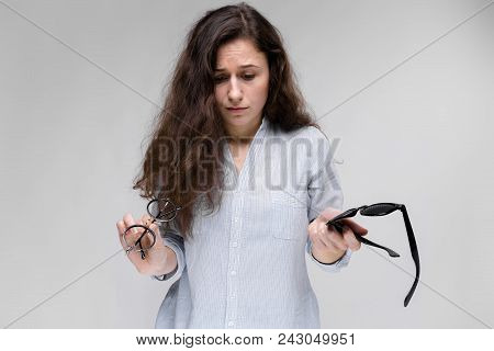 Young Girl With Glasses On A Gray Background. Portrait Of A Young Beautiful Girl. A Charming Girl In