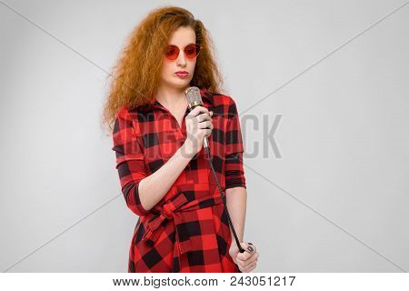 Charming Young Girl In A Checkered Cloth On A Gray Background