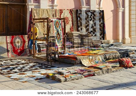 Sharm El Sheikh, Egypt - May 12, 2018: Unknown Young Man Sells Various Colorful Oriental Carpets On 
