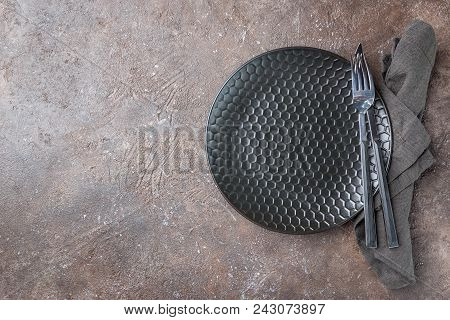 Empty Black Plate With A Napkin, Fork And Knife Over Dark Stone Background, Top View, With Copy Spac