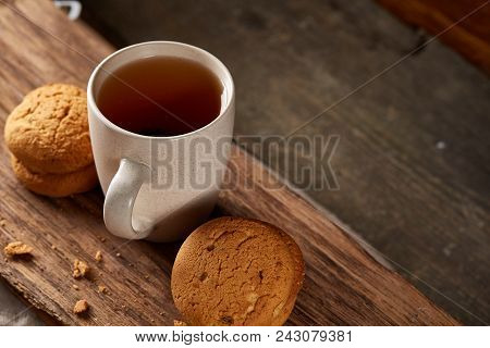 White Porcelain Mug Of Black Tea Or Earl Grey And Pile Of Sweet Cookies On Flat Piece Of Wood Over R