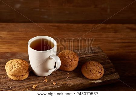 White Porcelain Mug Of Black Tea Or Earl Grey And Pile Of Sweet Cookies On Flat Piece Of Wood Over R