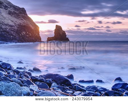 Cloudy Evening On Rocky Shore At Sunset. Sunset Mirroring In  Sea Water And Large Cracked Rocks With