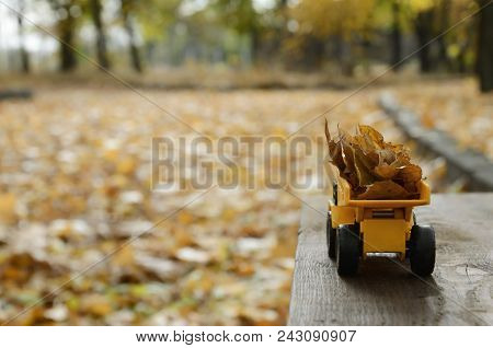 The Concept Of Seasonal Harvesting Of Autumn Fallen Leaves Is Depicted In The Form Of A Toy Yellow T