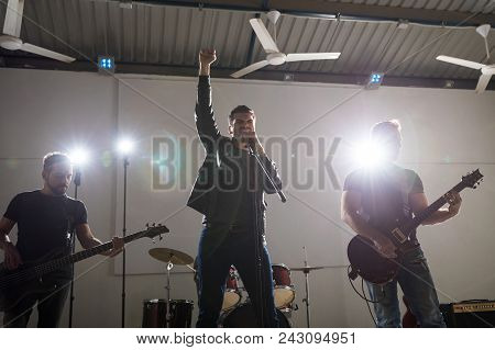 Lead Singer With Two Guitarist Performing Hard Rock Music On Stage