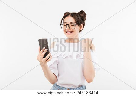 Photo of lovely woman with double buns hairstyle smiling with dental braces on teeth while chatting on smartphone isolated over white background