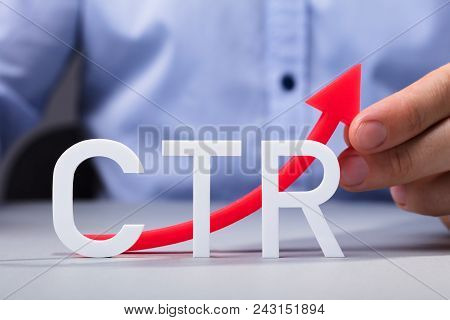 Close-up Of A Man Touching Increasing Red Click Through Rate Arrow On Desk