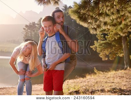 Portrait Of Family Pulling Faces On Walk By Lake