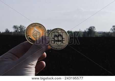 The Guy Holds The Coins In His Hands. Crypto Currency In The Hands Of A Person. Two Manettes On The 