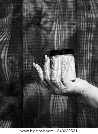 Female Hand Smeared In Golden Glister Holding Jar With Colorful Paint On Brown Vintage Studio Backgr