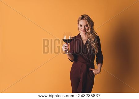 Portrait Of Positive Cheerful Big-eyed Woman In Suit Having Glass With Red Wine, Alcohol Beverage In