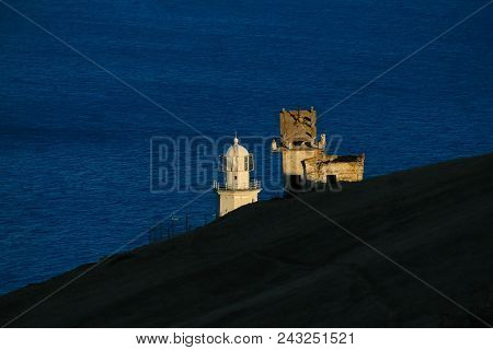 The Lighthouse At Sunset In The Twilight In Clear Weather At Cape Meganom, The East Coast Of The Pen