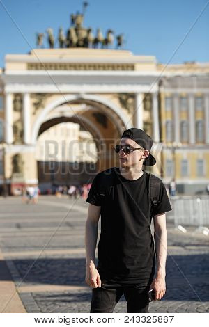 Young Stylish Man Tourist Walking Near General Staff Builsing Arch In The Palace Square In St. Peter
