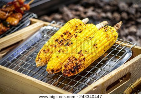 Grilled Corn On The Grill With Blur Bbq Beside.