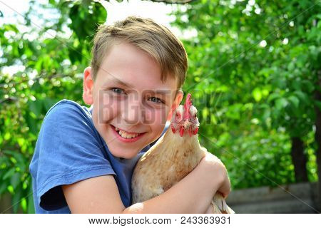 The Boy Is Holding A White Chicken And Smiling
