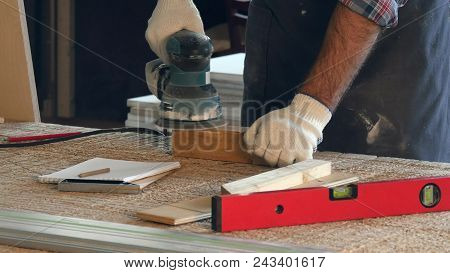 Man Working With Wooden Planck And Electric Planer In Workshop