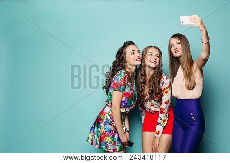 Fashionable Women Wearing In Brigth Clothes Spending Time Together, Making Photo At Smart Phone.thre