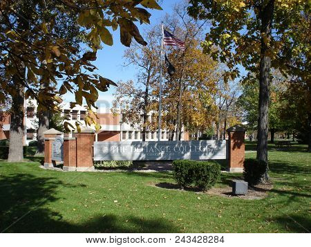 Defiance College Sign And Flag Pole With The United States Of America Flag Surrounded By Fall Foliag