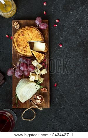 Cheese Platter With Assorted Cheeses, Grapes, Nuts Over Black Background, Copy Space. Italian Cheese