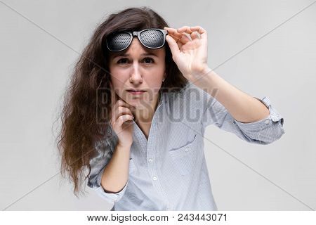 Young Girl With Glasses On A Gray Background. Portrait Of A Young Beautiful Girl. A Charming Girl In