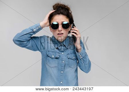 Young Girl In Round Glasses On A Gray Background. Portrait Of A Young Beautiful Girl. Charming Girl 