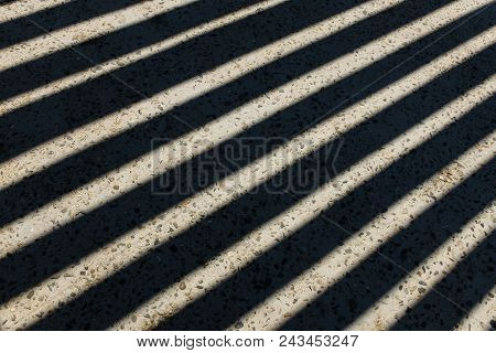 Sunlight Shines Through Wooden Fence And Makes Geometric Stripes Shadows On The Ground. Shadows Of W