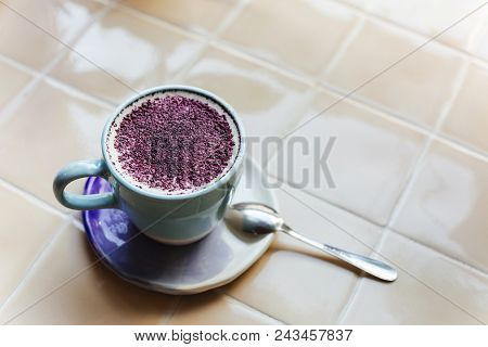 Lavender Latte In A Light Blue Cup On A Table With Ceramic Tile Top. Lavender Latte Is Made Of Laven