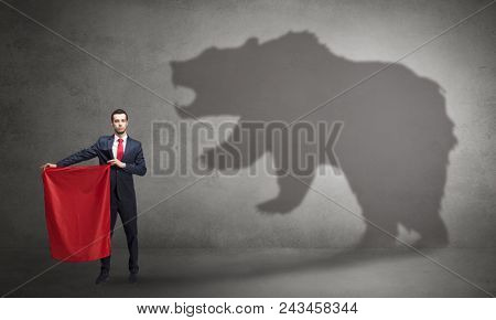 Businessman standing with red cloth in his hand and big bear shadow on his background