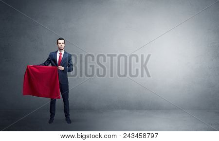 Businessman standing with red toreador cloth in his hand in an empty room