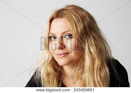Pretty Adorable Woman With Pleasant Smile Looks Directly Into Camera, Isolated Over Gray Background.
