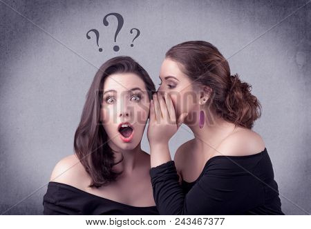 A teenager girl looking confused with drawn question marks above the head, while a girlfriend whispers something in her ear concept.