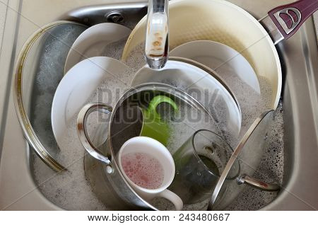 Dirty Dishes And Unwashed Kitchen Appliances Filled The Kitchen Sink
